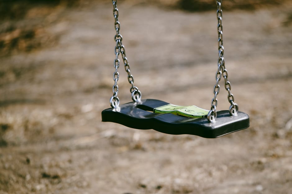 Close-up of an empty swing with chains in an outdoor playground.