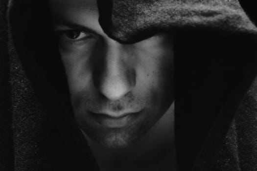 Close-up black and white portrait of a serious man wearing a hood.
