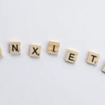 Wooden tiles on a white background spell anxiety, symbolizing mental health awareness.