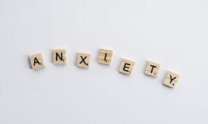 Wooden tiles on a white background spell anxiety, symbolizing mental health awareness.