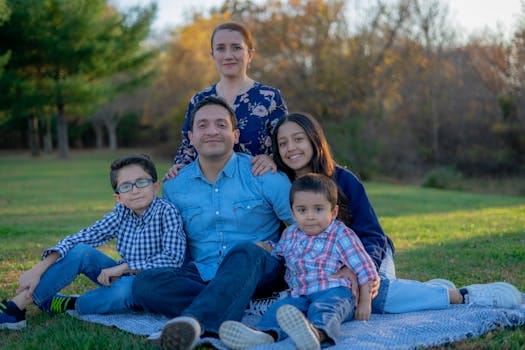 A joyful family sitting together on grass in a park with warm smiles.