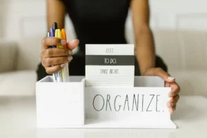 Close-up of hands organizing pens and notes in a white box labeled 'Organize.' Perfect for productivity inspiration.