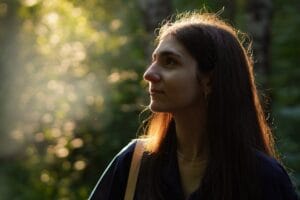 Profile of a woman in a sunlit forest, exuding tranquility and natural beauty.